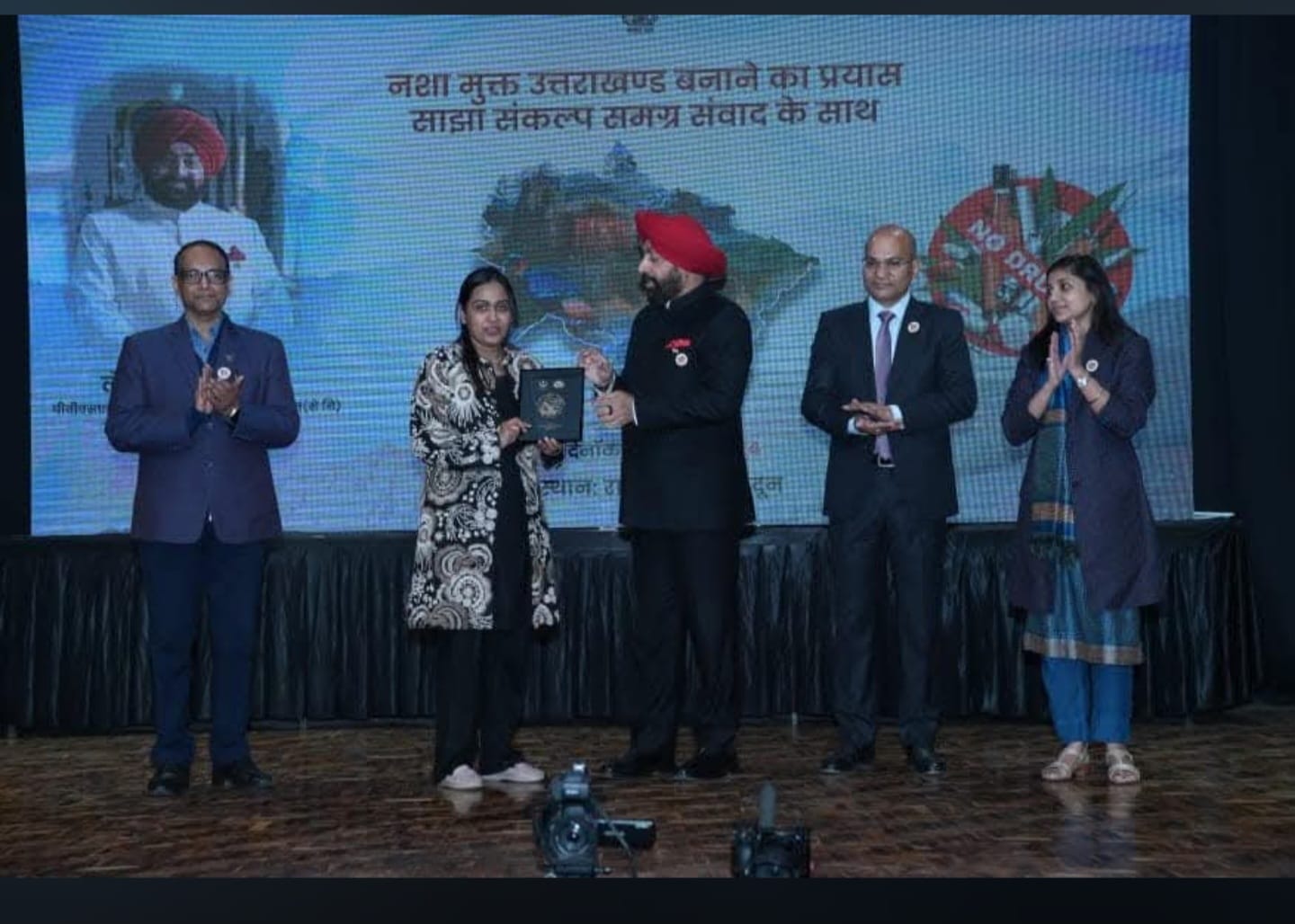 Dr. Nisha Singla on stage with the Governor of Uttarakhand